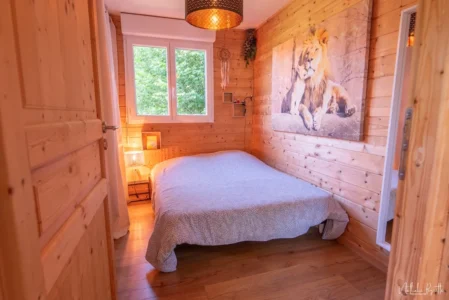 Chambre en bois avec lit double, tableau de lion et lumière douce.