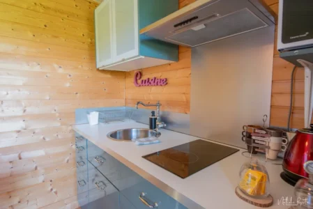 Cuisine compacte du chalet avec évier, plaques, bouilloire et vaisselle.