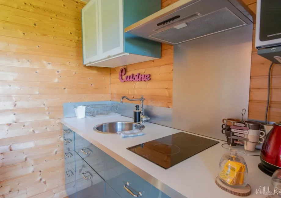 Cuisine compacte du chalet avec évier, plaques, bouilloire et vaisselle.