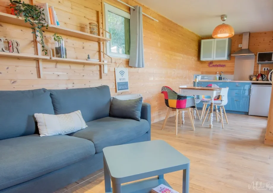 Vue intérieure du chalet Bien-Hêtre, en bois avec canapé, salon et kitchenette en fond.