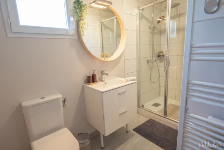 Salle d’eau du chalet avec vasque, miroir rond et douche vitrée.