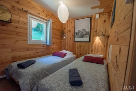 Chambre avec deux lits simples dans un lodge en bois, ambiance chaleureuse et naturelle.