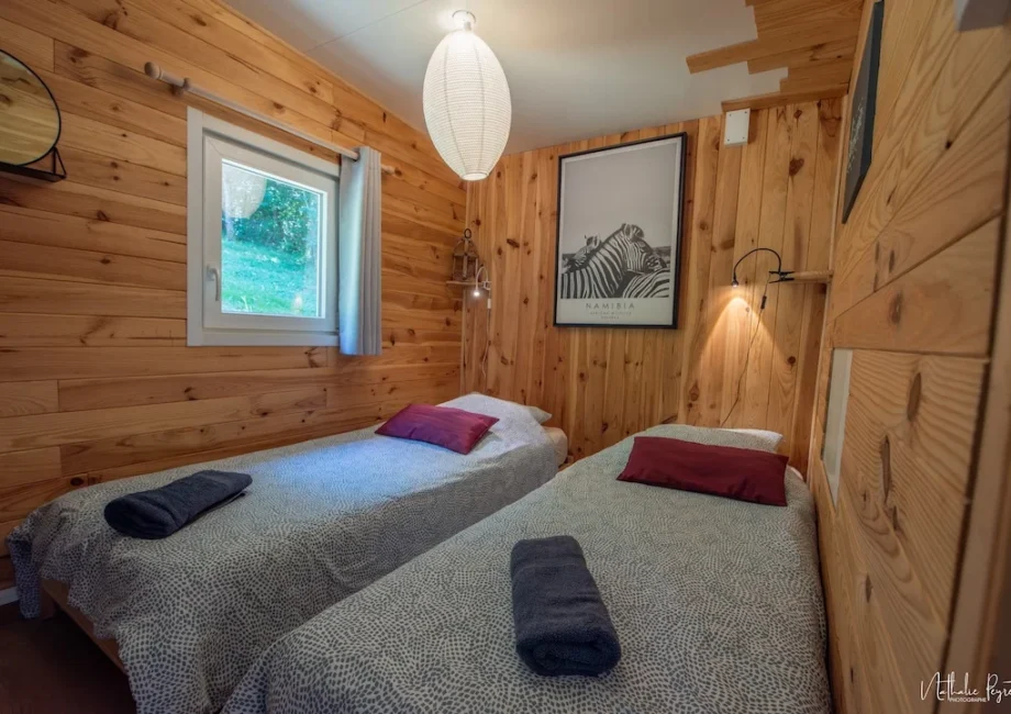 Chambre avec deux lits simples dans un lodge en bois, ambiance chaleureuse et naturelle.