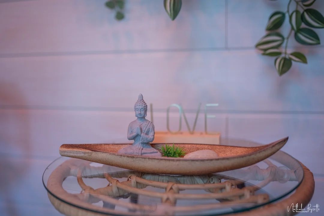 Plateau de décoration zen avec statuette de Bouddha, galet et végétaux.
