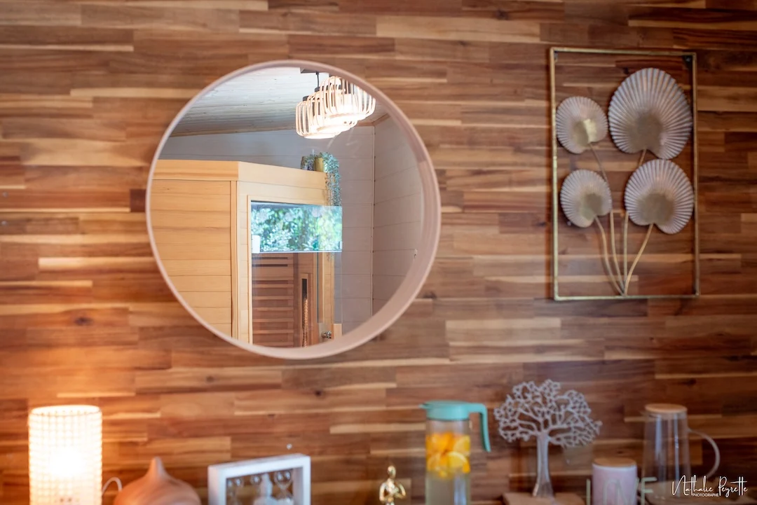 Détail d’un miroir reflétant un sauna dans une pièce en bois.